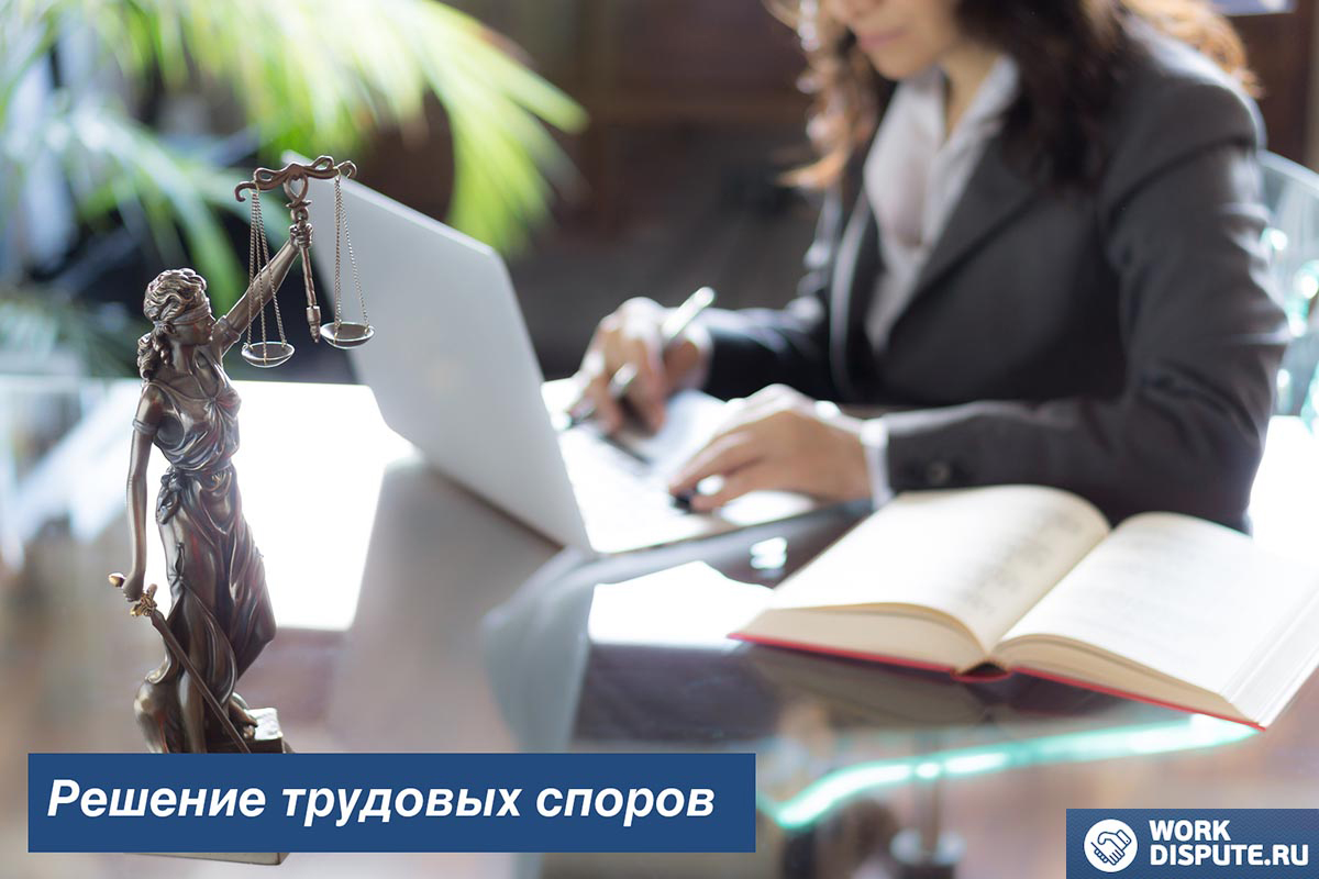 статуя справедливости на фоне женщины, работающей за компьютером